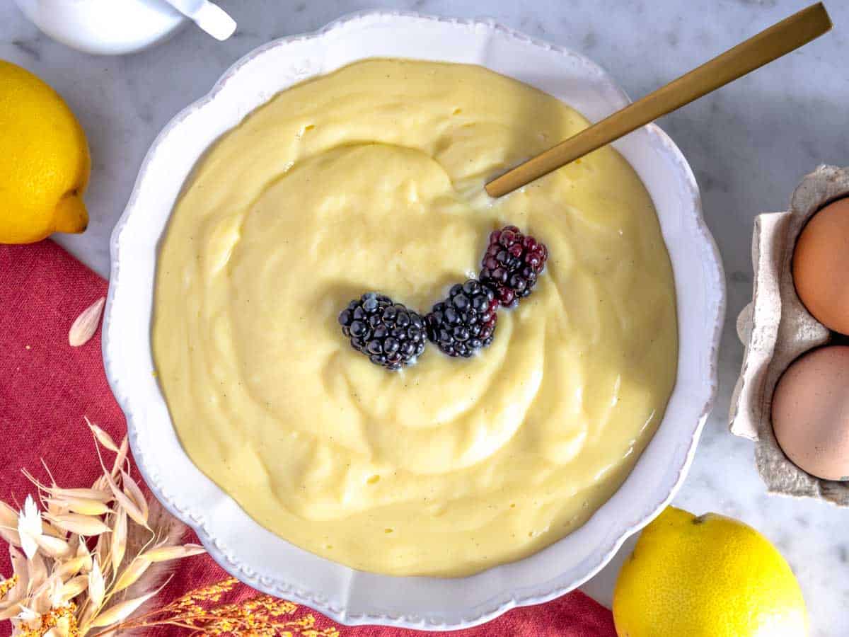 Crema pasticcera con un cucchiaio e more.