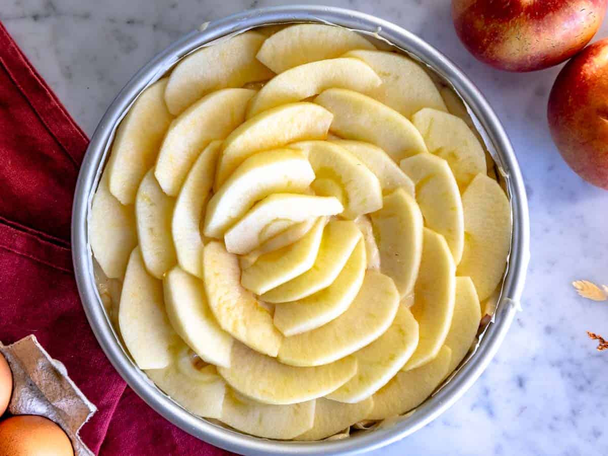 Torta di mele con uno strato di mele tagliate a fettine sottili.