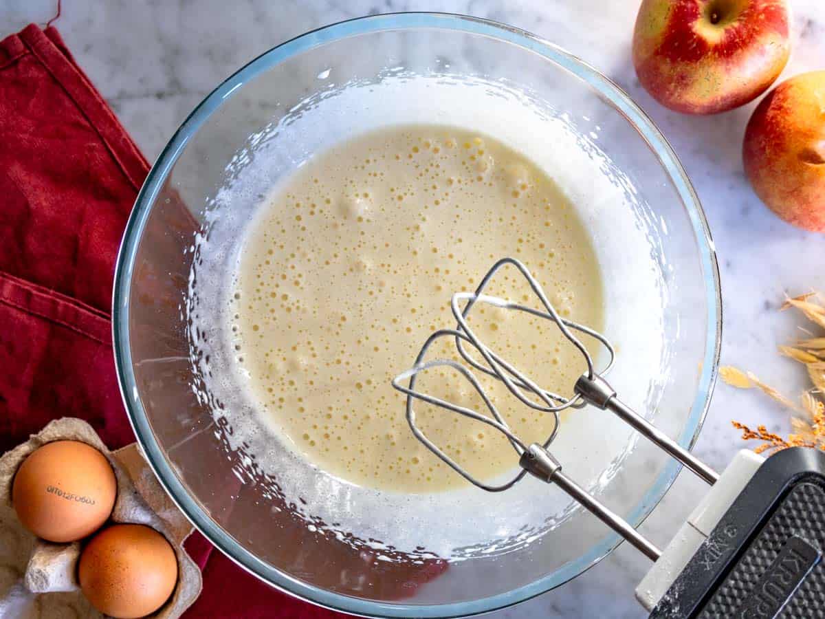 Impasto della torta di mele mescolato con fruste elettriche.