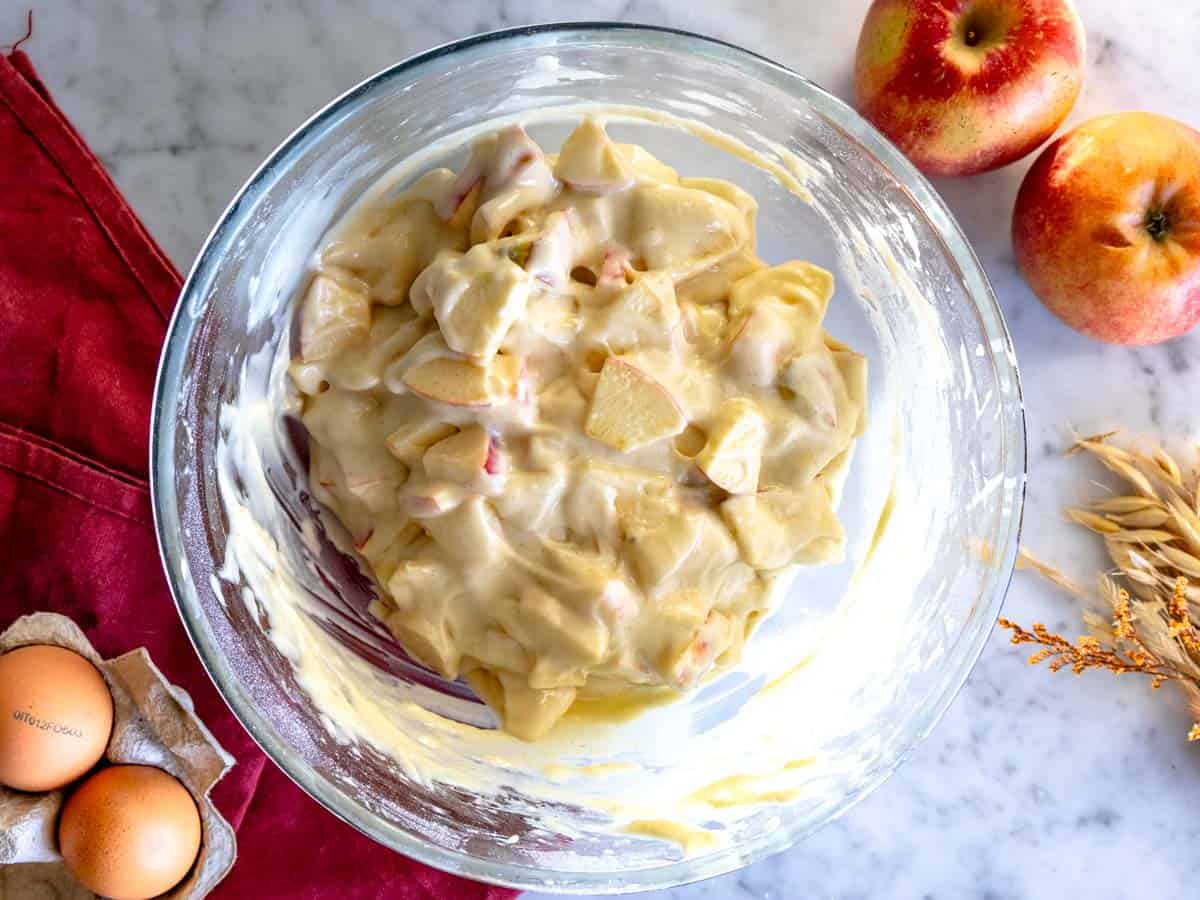Pezzi di mela incorporati nella pastella per la torta di mele.