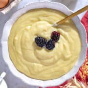 Crema pasticcera in una ciotola bianca con more.