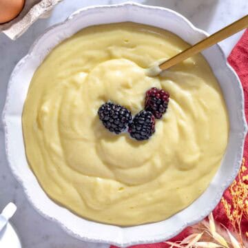 Crema pasticcera in una ciotola bianca con more.