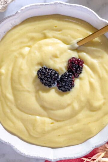 Crema pasticcera in una ciotola bianca con more.
