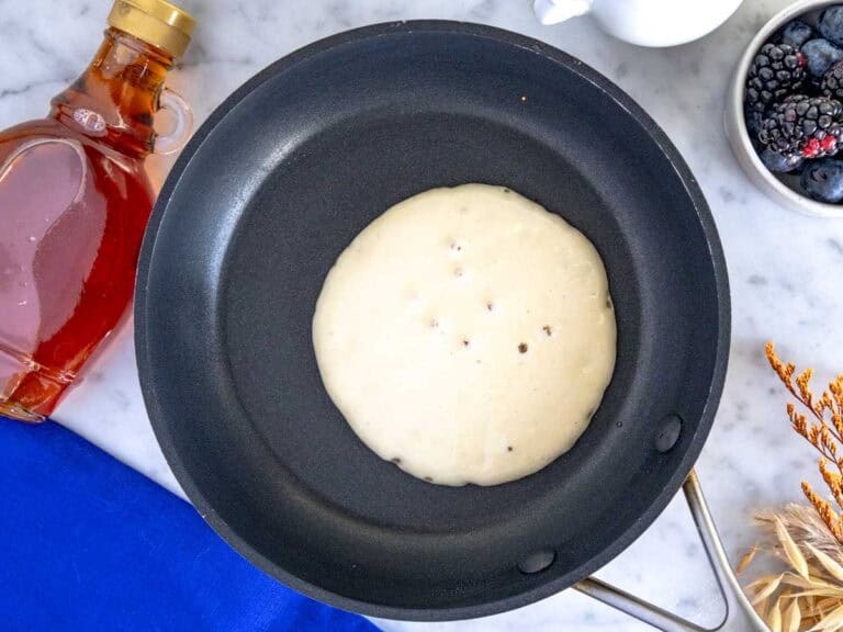 Una pancake che cuoce in una piccola padella nera.