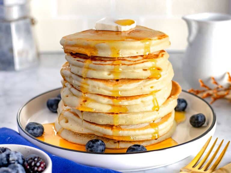 Una pila di pancake su un piatto bianco.