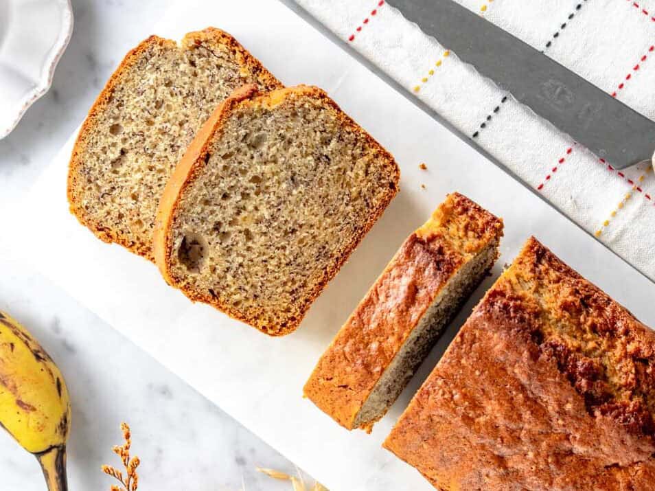 Banana bread su un tagliere di marmo bianco tagliato a fette.