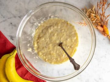 Banana schiacciata insieme agli ingredienti liquidi in una ciotola.