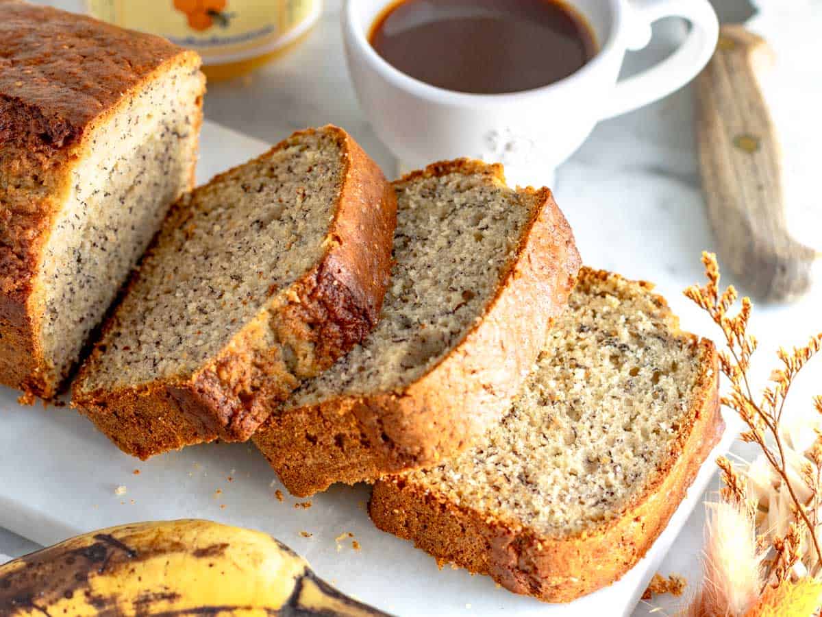 Banana bread a fette e servito con una tazza di caffè.