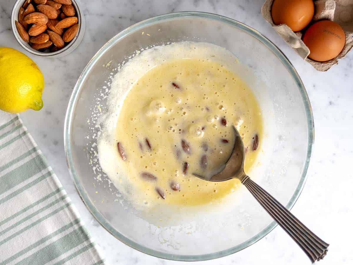 gli ingredienti liquidi e le mandorle in una ciotola di vetro.