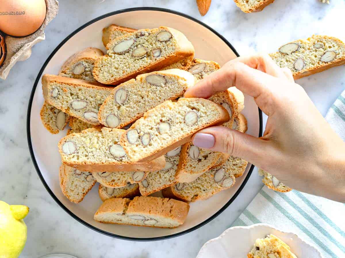 Cantucci sul piatto con una mano femminile.